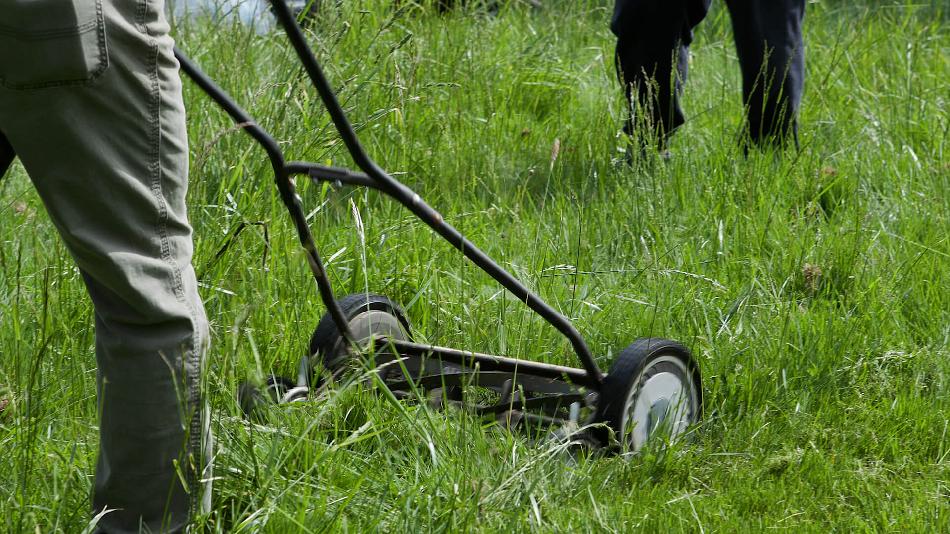 person mowing with push mower